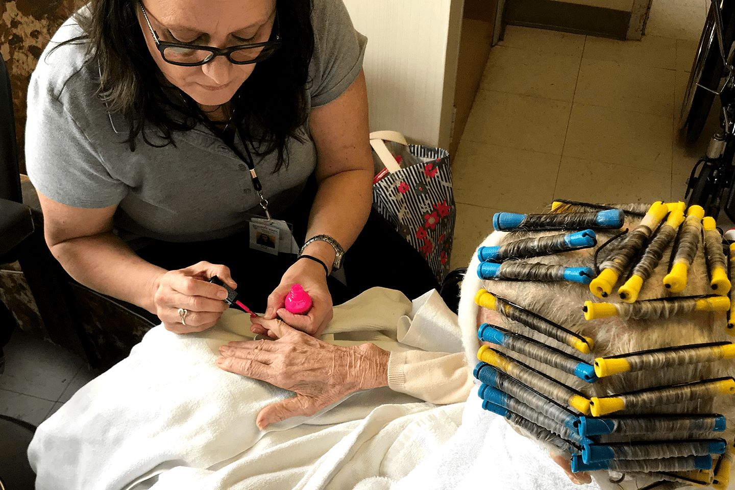 A lady putting nail polish on a hand of another person.